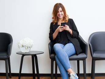 Patientin schaut im Wartezimmer aufs Handy